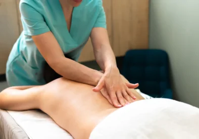 Terapeuta realizando un masaje en la espalda de un paciente en un entorno clínico, enfocado en la relajación y el bienestar.