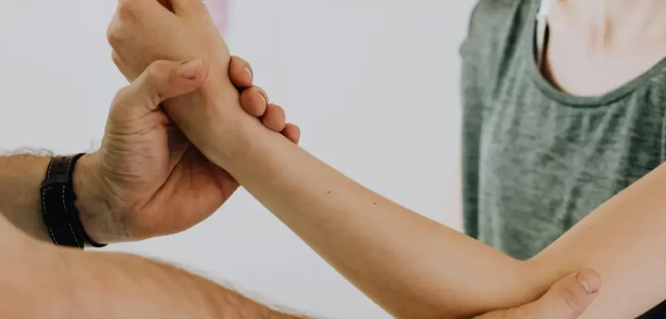 Terapia física en acción, mostrando a un profesional ayudando a una mujer con ejercicios de rehabilitación en el brazo.
